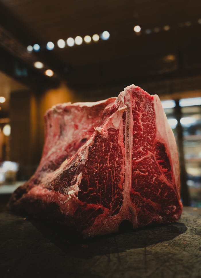Mastering the First Impression: Your intriguing post title goes here Close-up of a raw marbled beef cut on a wooden surface in a warm kitchen setting.